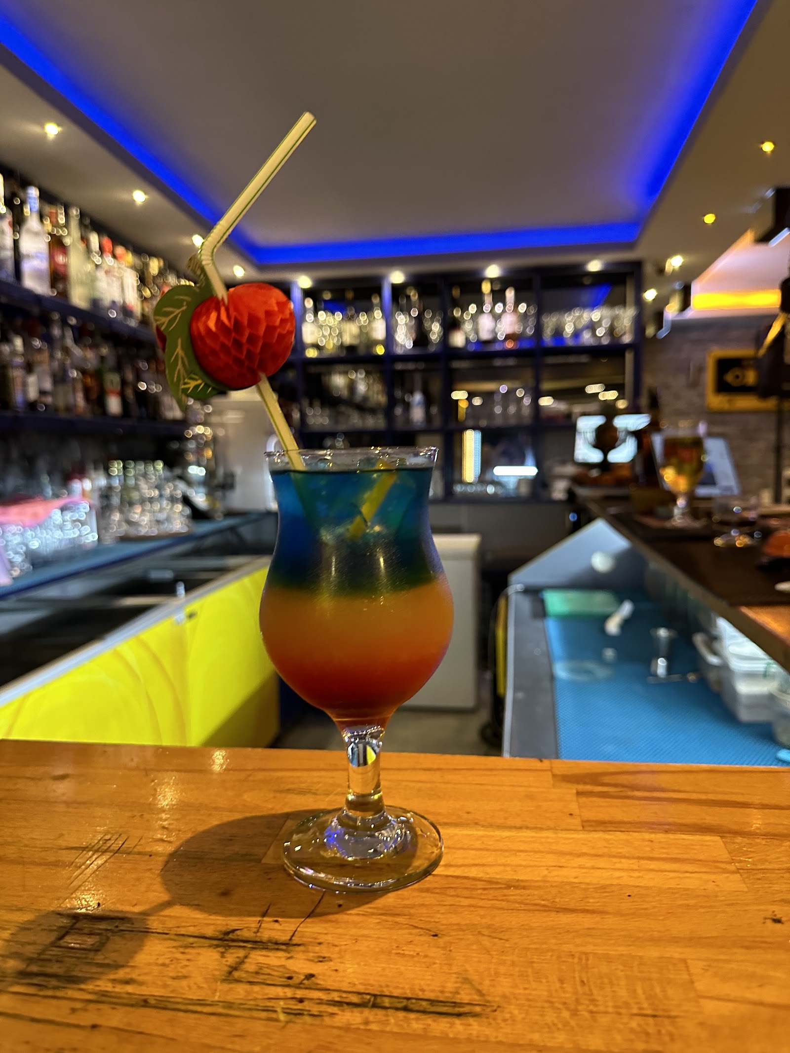 Layered blue and orange cocktail on the wooden bar counter