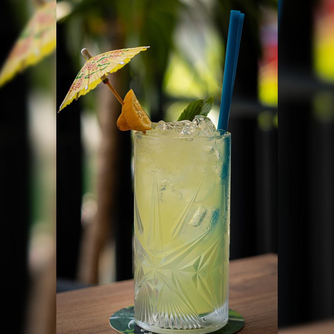 Tall glass of homemade lemonade with ice, mint and a paper umbrella