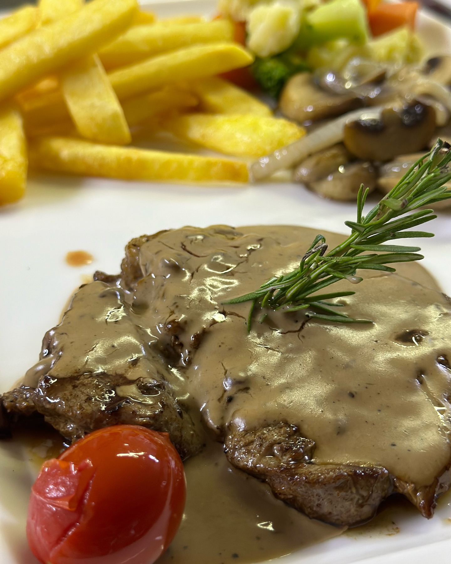 Pepper steak in creamy pepper sauce with rosemary, chips and mushrooms