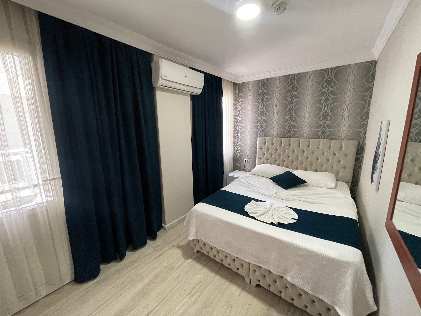 Double room with a tufted grey headboard, navy curtains and air conditioning